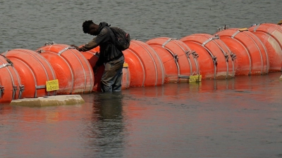 Ein Mensch aus Kolumbien steht an einer schwimmenden Bojenbarriere, um den Rio Grande von Mexiko in die USA zu überqueren. (Foto: Eric Gay/AP/dpa)