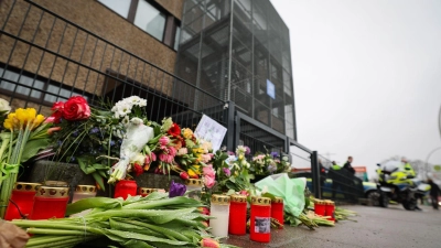 Blumen und Kerzen vor dem Eingangsbereich eines Gemeindehauses der Zeugen Jehovas. Nach der Amoktat in den Räumen der Zeugen Jehovas in Hamburg dauern die Ermittlungen an. (Foto: Christian Charisius/dpa)