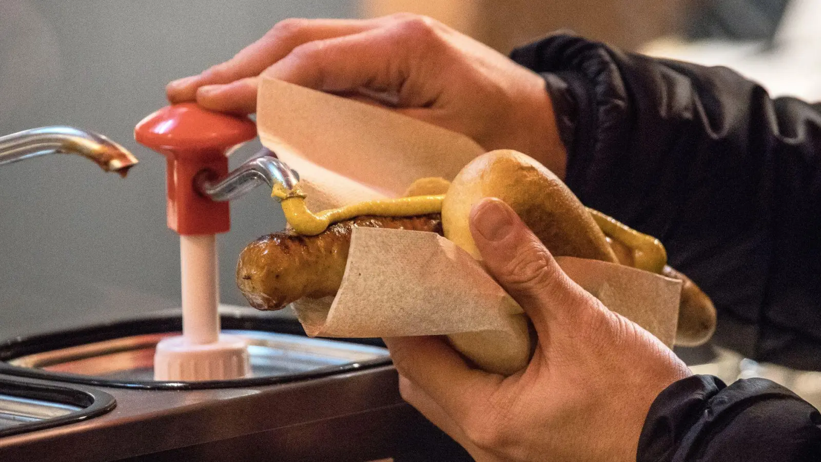 Mhh, noch etwas Senf! Mitgebrachte Speisen sind in der Regel erlaubt, das gilt auch für Bratwurst. (Foto: Sascha Thelen/dpa/dpa-tmn)