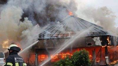 Einsatzkräfte der Feuerwehr sind bei Löscharbeiten vor einem brennenden Gebäude im Einsatz. (Foto: Markus Dorer/dpa)