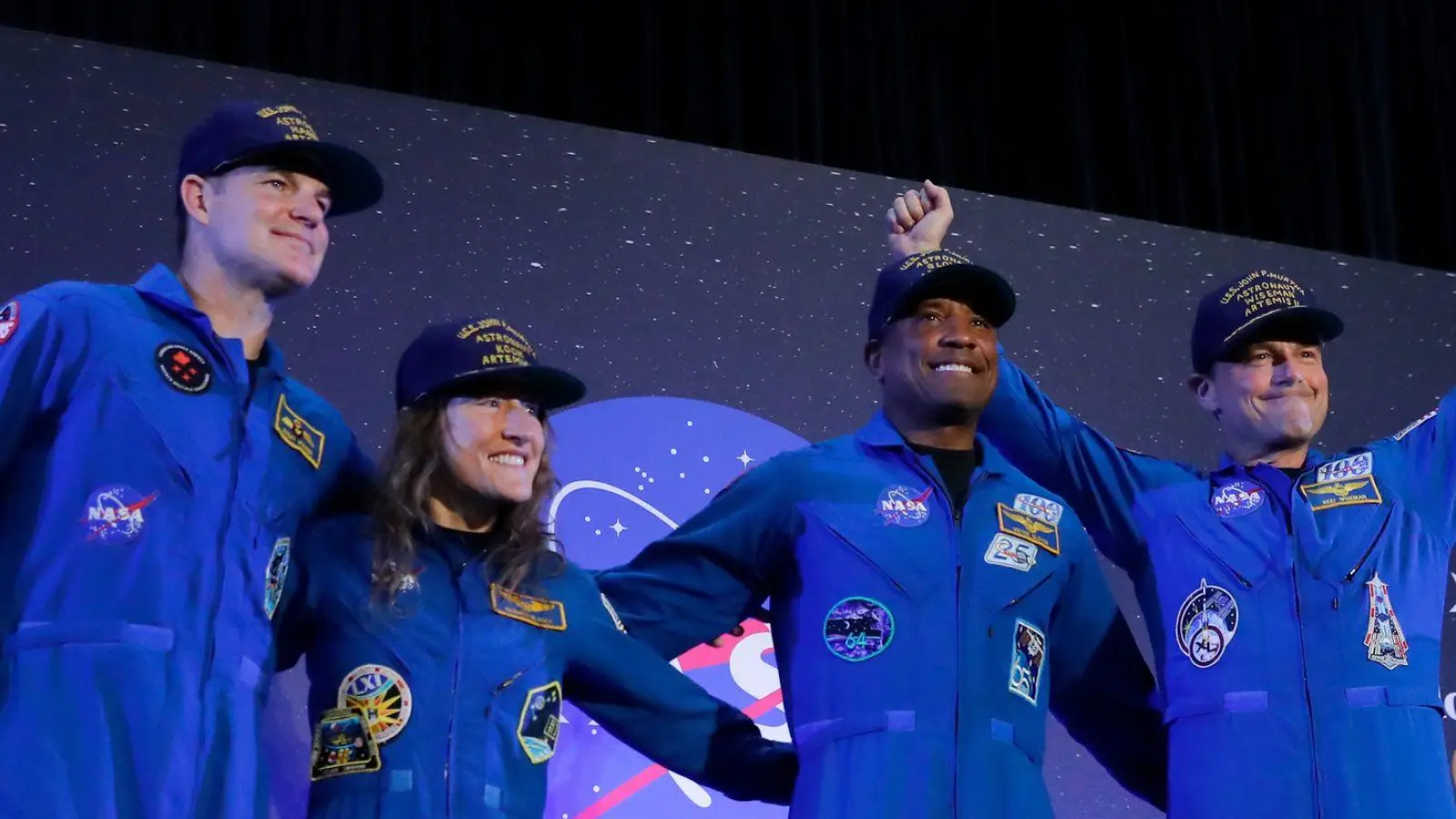 Die „Artemis 2“-Crew, Jeremy Hansen (l-r), Christina Koch, Victor Glover und Reid Wiseman, kommt am Ende einer Rückkehrfeier in die Mitte einer Bühne. (Foto: Michael Wyke/AP/dpa)