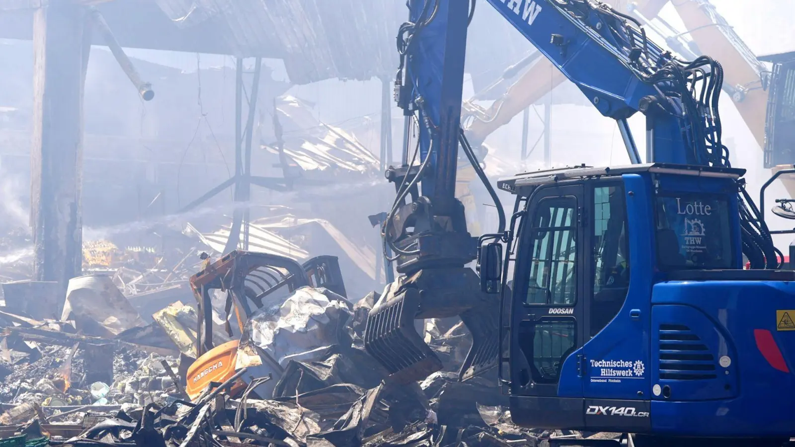 Einsatzkräfte des Technischen Hilfswerks (THW) beseitigen mit einem Bagger Schutt nach einem Feuer in einem Gewerbegebiet in Stuttgart. (Foto: Enrique Kaczor/dpa)
