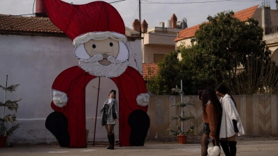 Eine junge Frau posiert für ein Foto an einer Weihnachtsdekoration auf einem Platz in einem christlichen Viertel in der syrischen Stadt Homs. (Foto: Leo Correa/AP/dpa)