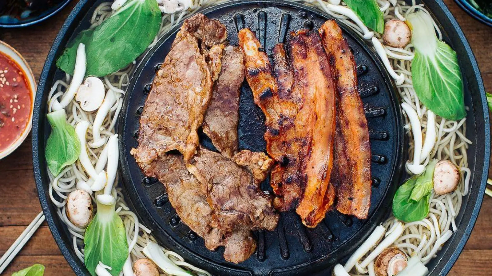 Koreanisches BBQ ist die beliebte Methode, Fleisch direkt am Esstisch zuzubereiten. Mariniertes Fleisch wird gegrillt, anschließend in ein Salatblatt gewickelt und in eine scharfe Sauce getunkt. Das genießt man zusammen mit verschiedenen Beilagen und Sauce zum Dippen. (Foto: Simi Leistner/asiastreetfood.com/dpa-tmn)