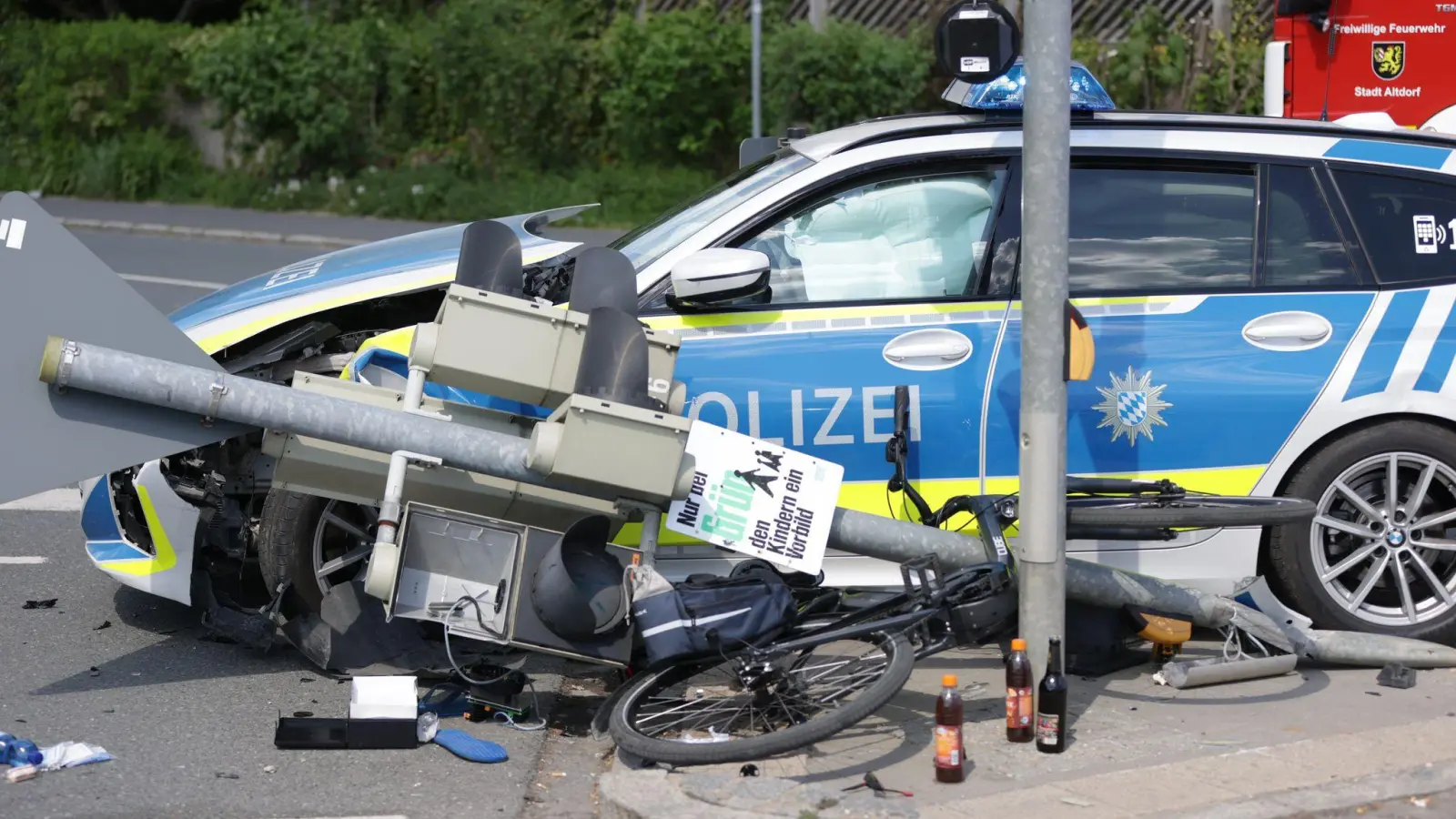 Ein Polizeiauto krachte in einen Ampelmast, der in einem Dominoeffekt umknickte und auf das Fahrrad eines Mannes stürzte.  (Foto: Goppelt/vifogra/dpa)
