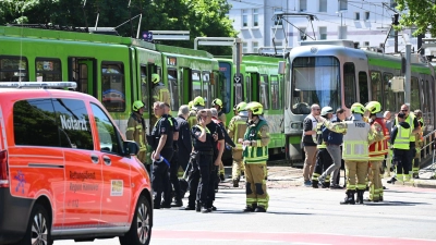 Einsatzkräfte von Polizei und Feuerwehr stehen nach einem Unfall neben zwei Stadtbahnen. (Foto: Julian Stratenschulte/dpa)