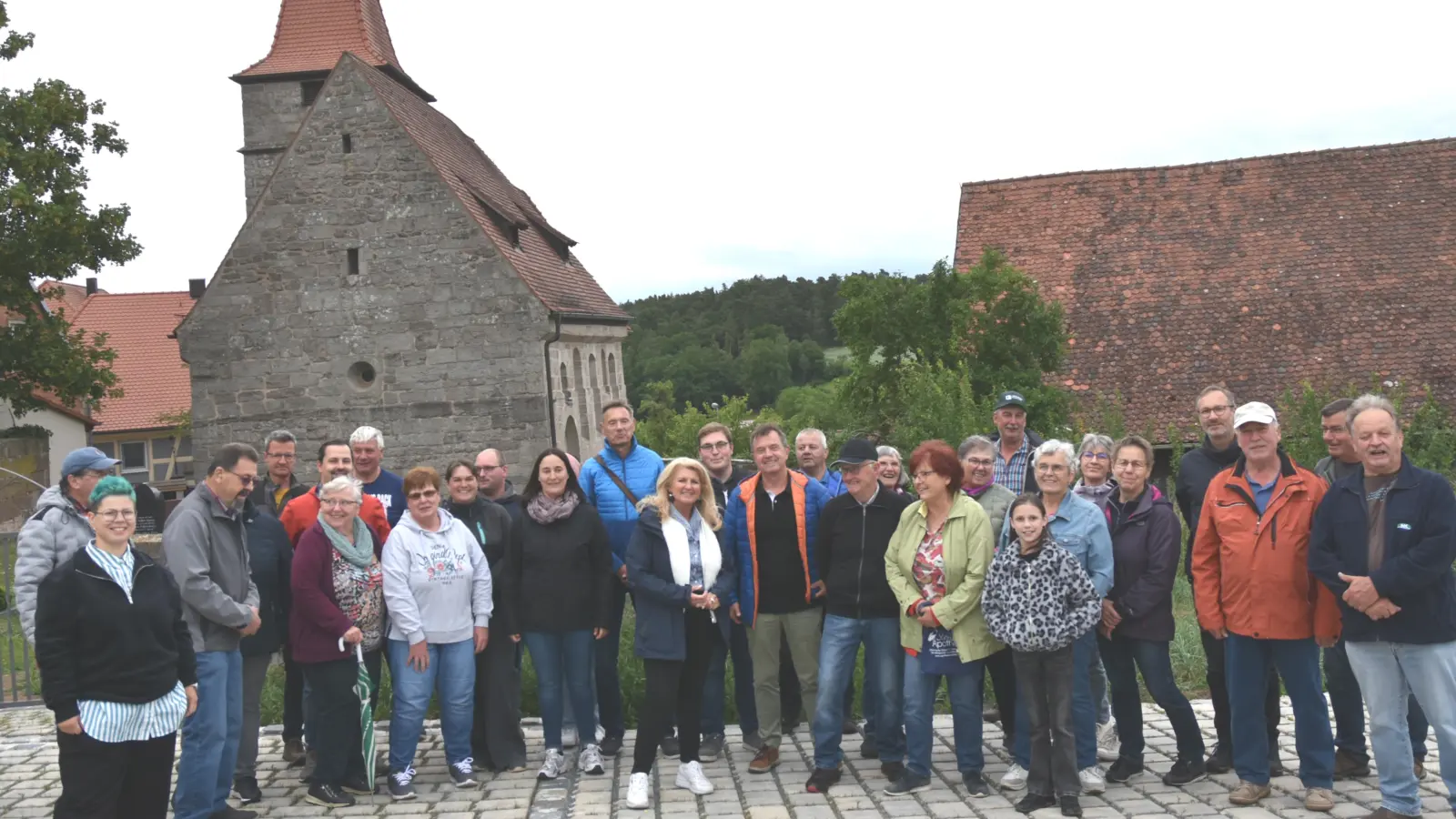 Großes Interesse zeigten die Jobstgreutherinnen und Jobstgreuther für ihre Dorferneuerung. Vor dem Friedhof und der Kirche St. Jobst wurden Parkplätze und die Zufahrt befestigt geschaffen. Pfarrerin Rebekka Schüler (links, grüne Haare) spendete den Segen über das aktuelle Werk. Bürgermeisterin Birgit Kreß (Mitte, weißer Schal) und DE-Vorsitzender Joachim Reindler (links neben ihr) hielten Ansprachen. (Foto: Anita Dlugoß)