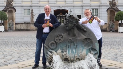 Die Macher Alexander Biernoth (links) und Michael Vogel zeigen das Werk auf dem Schlossplatz vor der Residenz. Der Brunnen namens Ansbacchantin von Jürgen Goertz ist im Stadtführer eigens erwähnt. (Foto: Oliver Herbst)