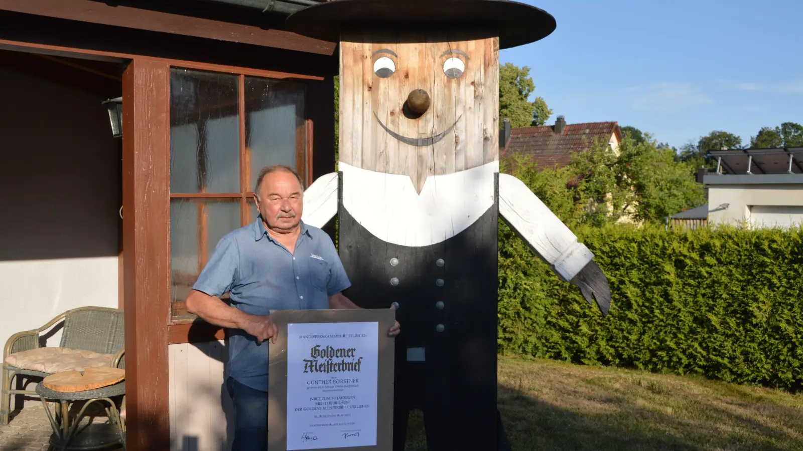Zwei Zimmermeister auf einem Foto: der eine aus Fleisch und Blut – der Burghaslacher Günther Borstner mit seinem Goldenen Meisterbrief –, der andere aus Holz, ein Internetfundstück. (Foto: Johannes Zimmermann)