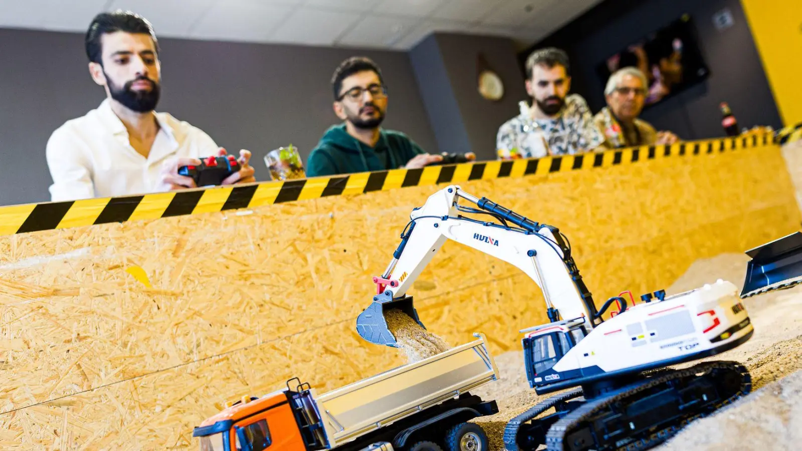 Gründer Siymo Othman (links) steuert mit Freunden kleine Bagger, Radlader und Lastwagen in seinem neu eröffneten Bagger-Café. Es soll das erste dieser Art in Deutschland sein. (Foto: Moritz Frankenberg/dpa)