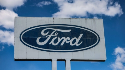Ein Logo steht vor dem Ford Werk bei gutem Wetter - wirtschaftlich gesehen sind die Perspektiven des Ford-Autogeschäfts in Europa düster. (Foto: Oliver Berg/dpa)