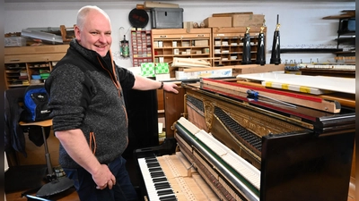 Rainer Wiedemann ist Klavierbaumeister aus dem Landkreis Ansbach. Hier ist er mit einem frisch reparierten Instrument in seiner Werkstatt zu sehen. (Foto: Anna Beigel)