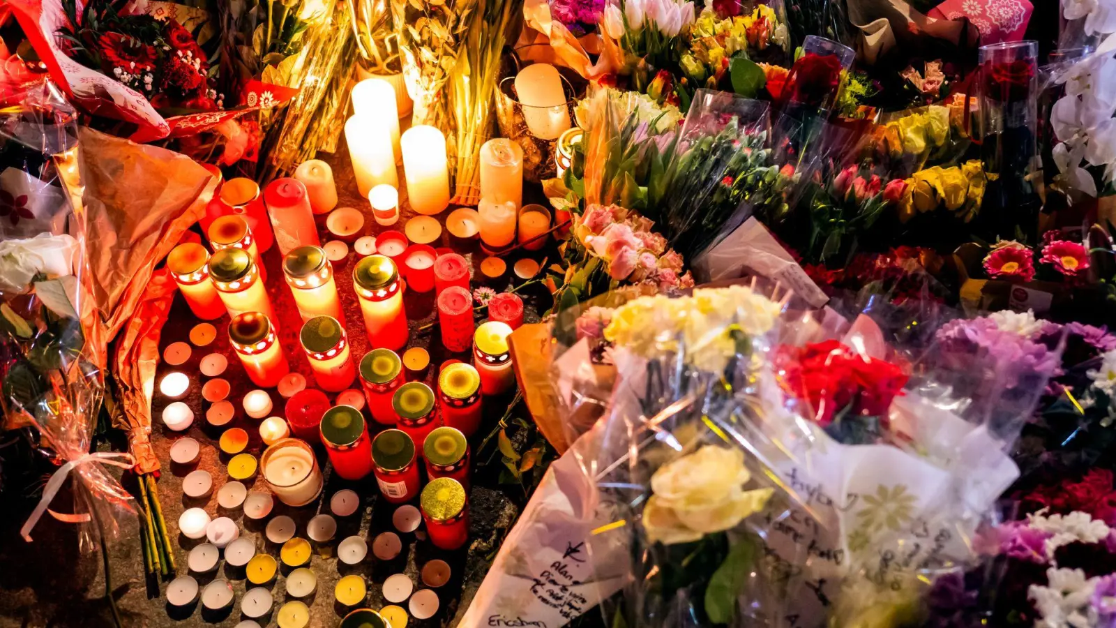 Ein Blumen- und Kerzenmeer erinnert an Tote und Verletzte in der Nähe des Brandortes.  (Foto: Jean-Christophe Bott/KEYSTONE/dpa)