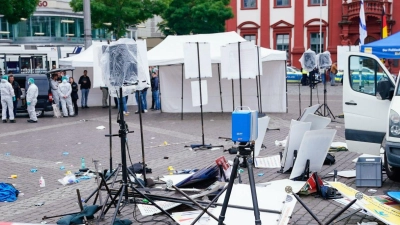 Mitarbeiter der Spurensicherung stehen auf dem Marktplatz hinter einem zertrümmerten Stand. (Foto: Uwe Anspach/dpa)