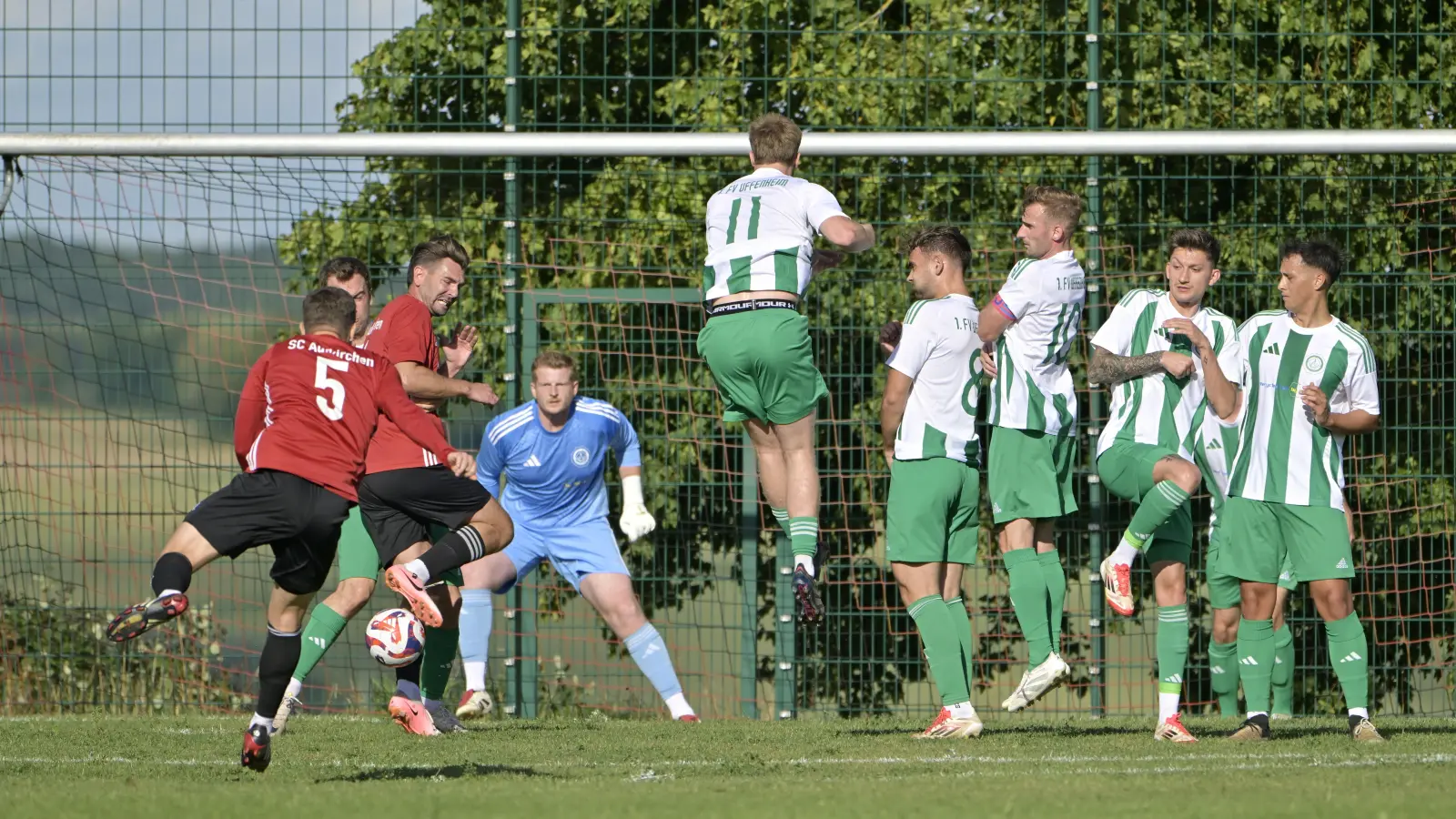 Daniel Holzmann (in rot mit der Nummer 5) bei einem Freistoß für den SC Aufkirchen, im Hintergrund FVU-Torwart Philipp Müller. (Foto: Martin Rügner)