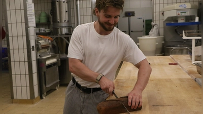 Friedrich Wimmer halbiert in seiner Bäckerei das Brot mit dem Messer und wiegt nicht nach. (Foto: Alexander Rausch)