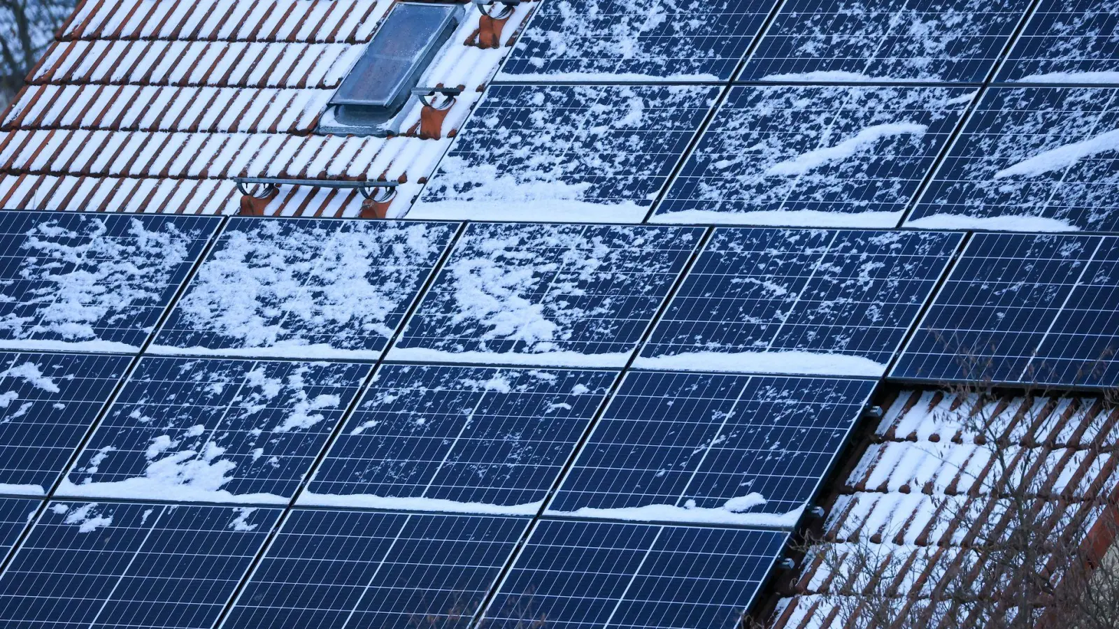 Schnee auf Solarmodulen kann im Winter den Stromertrag mindern: Doch das Abfegen von Schnee birgt Unfallgefahr und kann die empfindlichen Module beschädigen. (Foto: Jan Woitas/dpa/dpa-tmn)