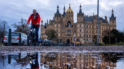 Fahrradfahrer vor dem Schweriner Schloss bei mildem, grauem Wetter in Norddeutschland. (Foto: Jens Büttner/dpa)
