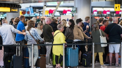 Reisende stehen in der Abflughalle des Amsterdamer Flughafens Schiphol Schlange. (Foto: Jeroen Jumelet/ANP/dpa)