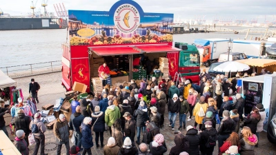 Besucher stehen am Morgen auf dem Hamburger Fischmarkt an der Elbe an einem Verkaufsstand. Vor den Ständen der Marktschreier bilden sich häufig große Menschenansammlungen. (Foto: Daniel Bockwoldt/dpa)