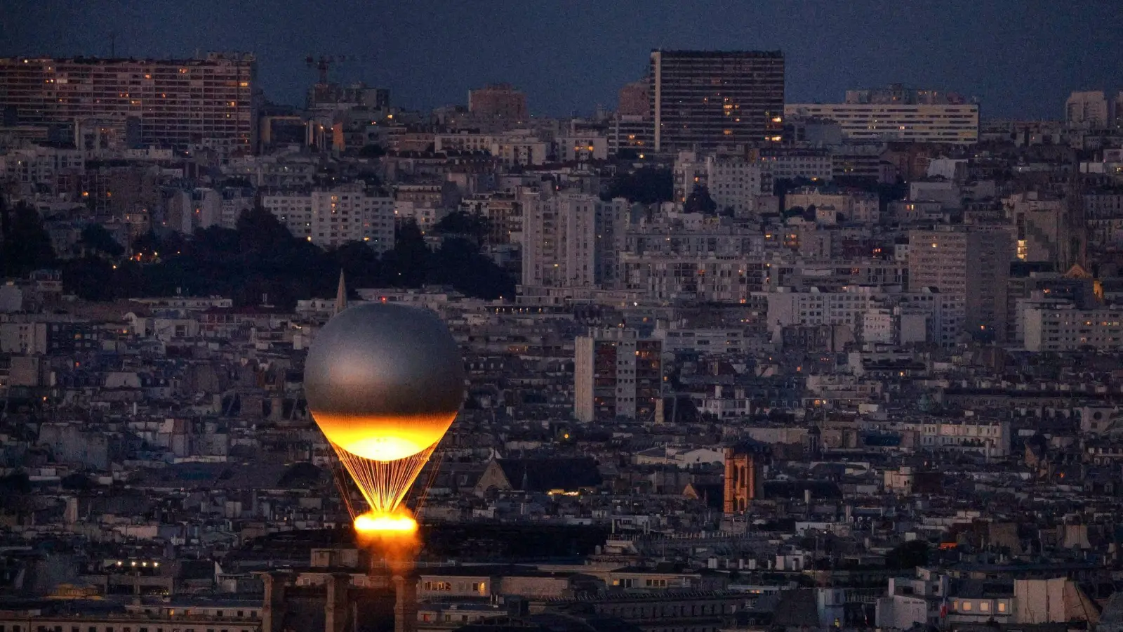 Der Kessel mit dem Olympischen Feuer fliegt an einem Ballon befestigt über Paris. Der Heliumballon stammt von einem darauf spezialisierten Unternehmen aus Augsburg. (Archivbild) (Foto: Geoffroy Van Der Hasselt/Pool AFP/AP/dpa)