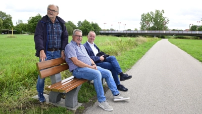 Peter Heinzel (Mitte), der Vorsitzende der Siedlergemeinschaft, und OB Thomas Deffner (rechts) sitzen auf der neuen Bank Probe. Heinzels Vize Reinhard Fichtner war bei der Übergabe im Bürgerpark dabei. (Foto: Jim Albright)