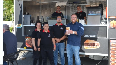 Köfteci Tarik eröffnete zusammen mit seiner Familie einen Imbissstand auf dem Parkplatz des ehemaligen Real-Marktes. Neustadts Bürgermeister, Alexander Müller, kostete gleich den ersten Köfte im Brot (rechts im Bild). (Foto: Christa Frühwald)