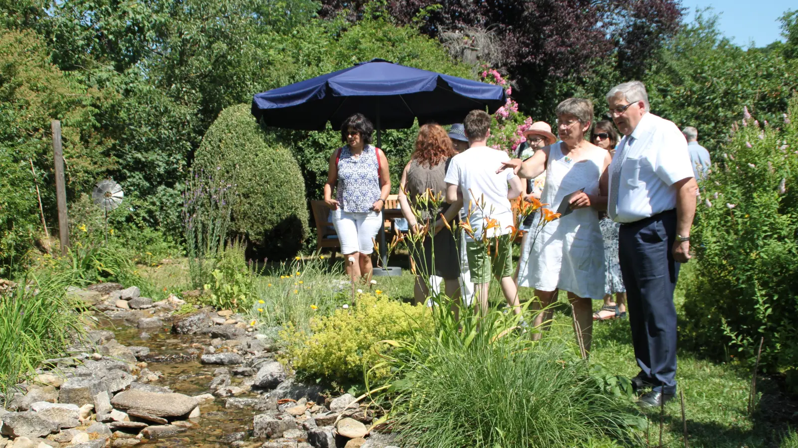 Gartenbesitzerin Gudrun Trabert erklärte nach der Eröffnung in Gollhofen Landrat Helmut Weiß ihre Anlage samt dem kleinen Bachlauf. (Foto: Hans-Bernd Glanz)