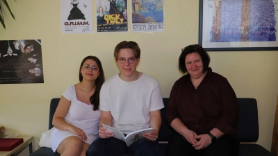 Emily Krauss und Manuel Manske aus dem Abiturjahrgang sehen mit Schulleiterin Andrea Pfeiffer einen Jahresbericht an (von links). (Foto: Oliver Herbst)