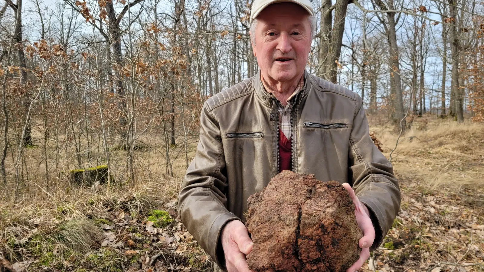 Hermann Emmert mit einem Brandlehm-Brocken, von denen auf dem Burgbernheimer Schlossberg so einige in ganz unterschiedlichen Größen herumliegen. (Foto: Nina Daebel)