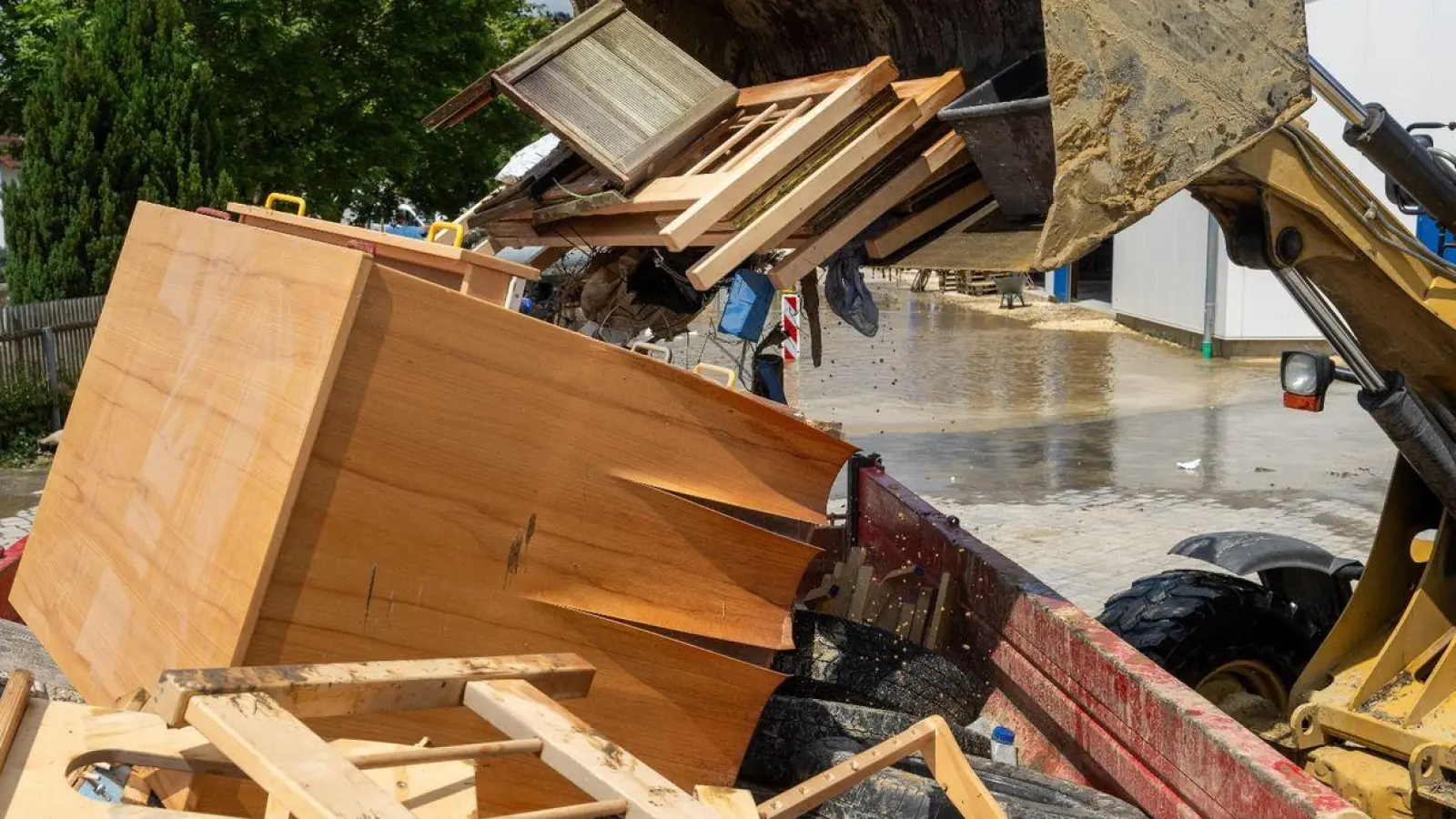 Im Bauhof wird mit einem Radlader der durch Hochwasser entstandene Sperrmüll in einen Container gekippt. (Foto: Stefan Puchner/dpa)