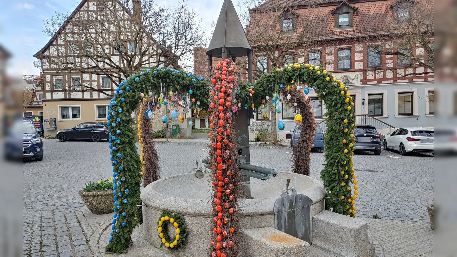 Der Obst- und Gartenbauverein hat den Brunnen am Marktplatz in Burgbernheim österlich geschmückt. Bunte Eier zieren die Bögen, die aus Tannenzweigen und Reisig gebunden wurden. (Foto: Katrin Merklein)