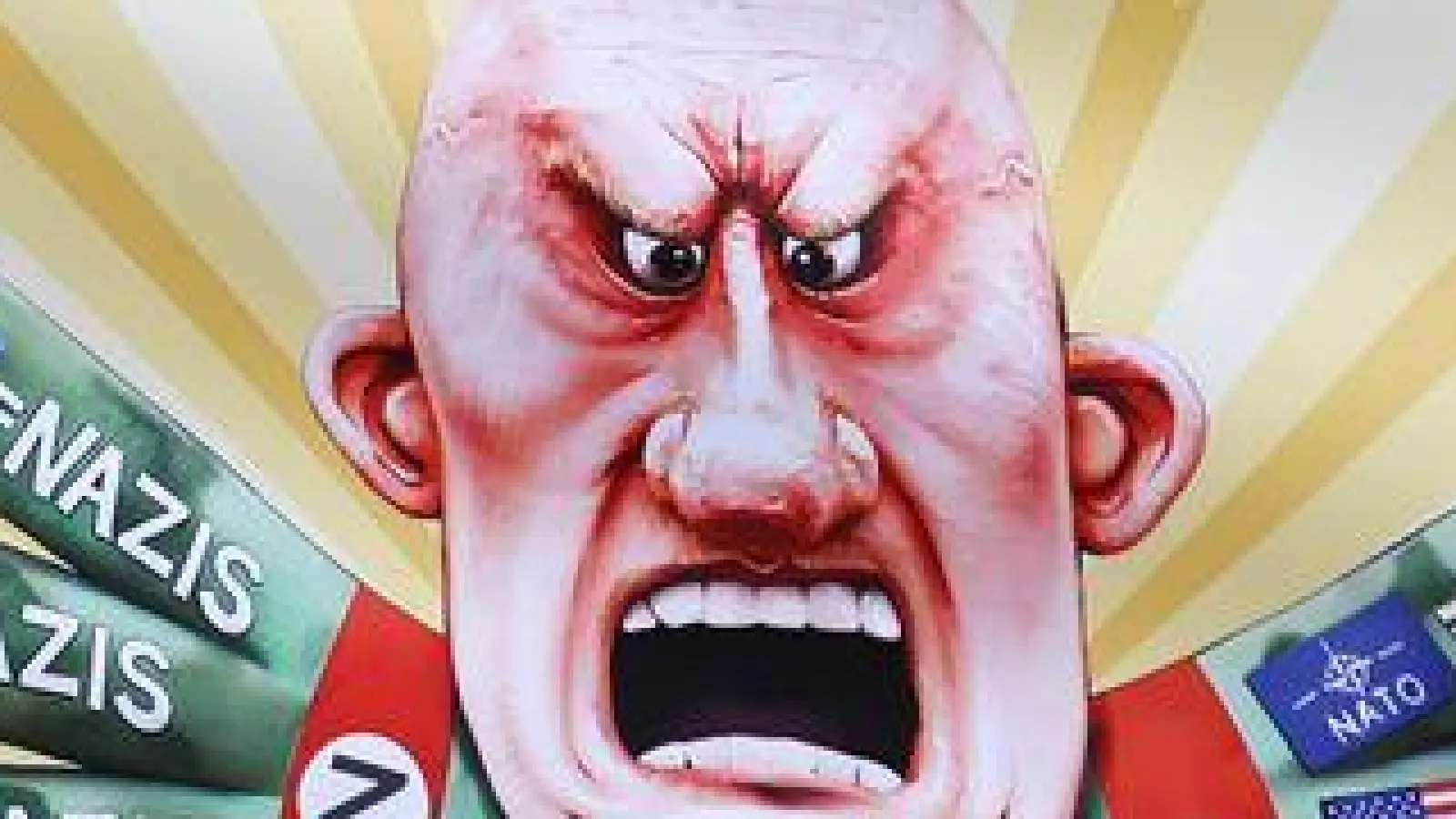 Der ukrainische Hilfsverein Blau-Gelbes-Kreuz hält Plakate mit Putin-Motiven hoch. Das ist als Zeichen der Solidarität mit Wagenbauer Jacques Tilly gemeint. Dieser wird in Russland strafrechtlich verfolgt.  (Foto: Oliver Berg/dpa)