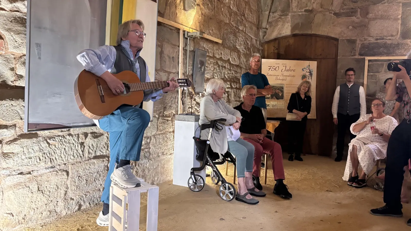 Walter Gramming eröffnete die Ausstellung musikalisch. Laudatorin Renate Schmidt (2.v.l. sitzend) stellte das Künstlerkollektiv in ihrer Eröffnungsrede vor.  (Foto: Nicole Gunkel)