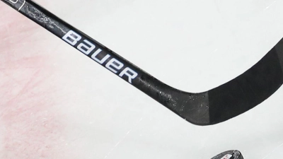 Ein Puck liegt vor einem Schläger im Spiel auf dem Eis. (Foto: Daniel Karmann/dpa)