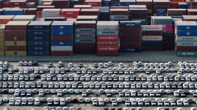 Neue Volvo-Fahrzeuge stehen neben Containern und warten auf ihre Verschiffung im Jangtse-Hafen in der Stadt Nanjing in der ostchinesischen Provinz Jiangsu. (Foto: Uncredited/CHINATOPIX/AP/dpa)