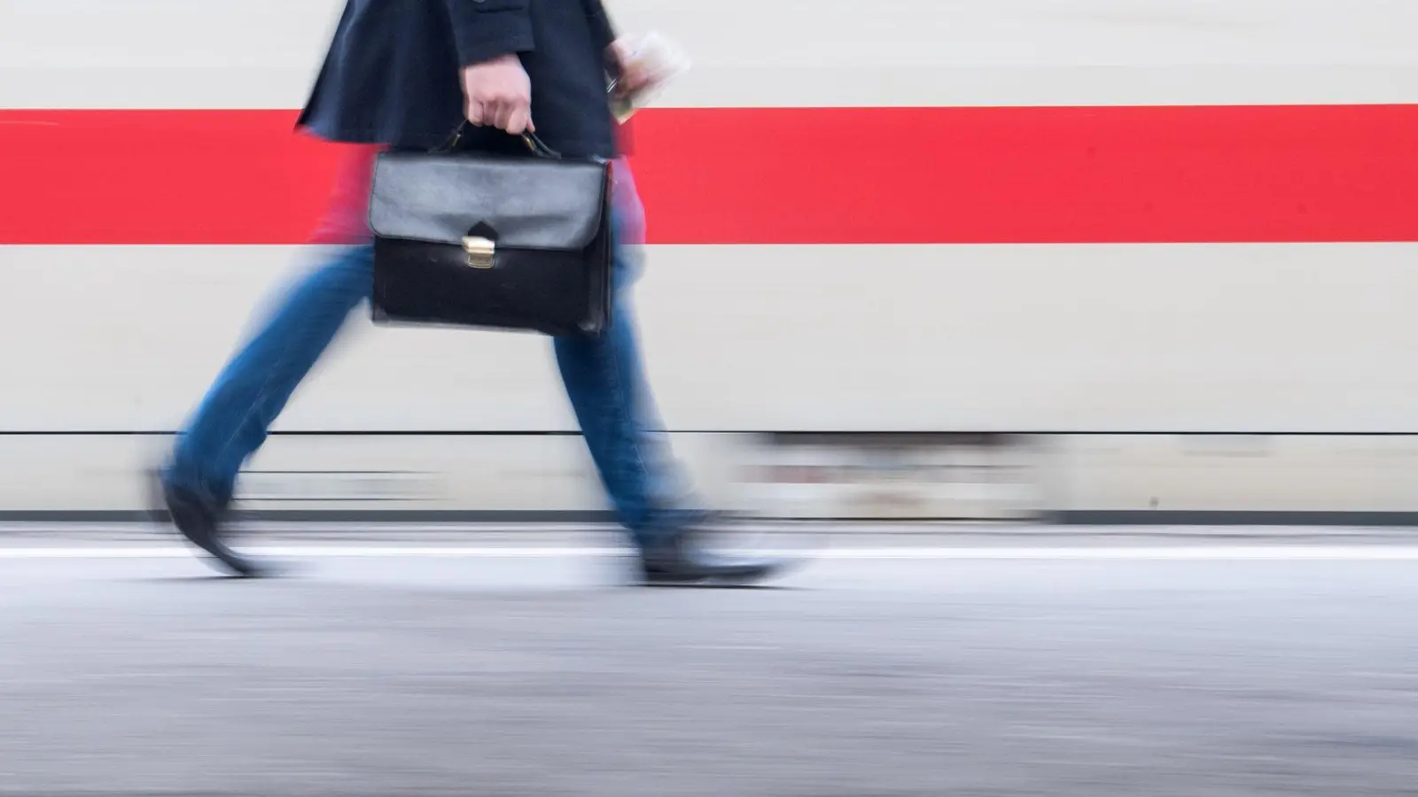 Ein Reisender hält eine Tasche und geht an einem ICE vorbei. (Foto: Sebastian Gollnow/dpa/Symbolbild)