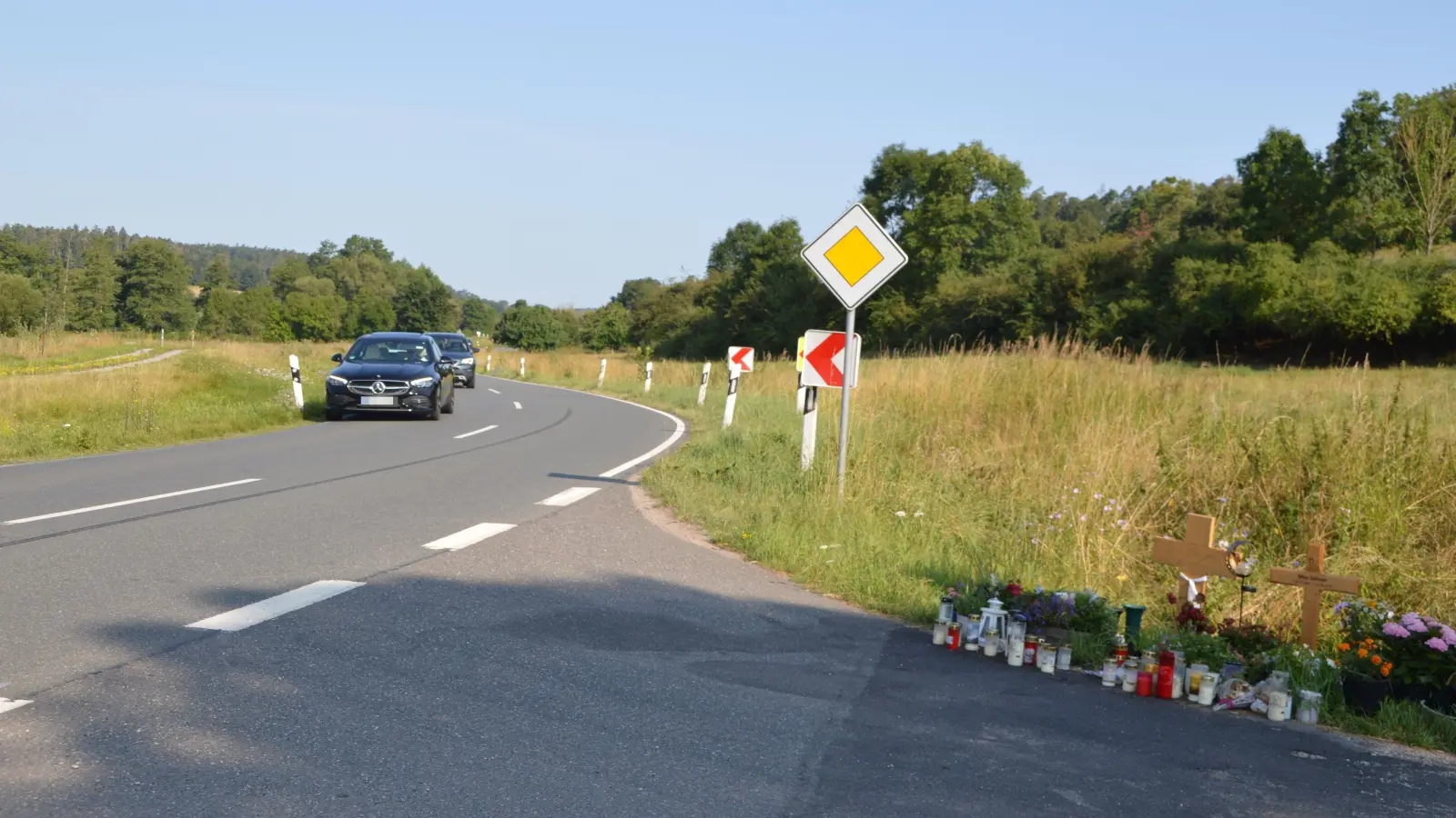 Kerzen, Blumen und Kreuze an einer Einmündung zur Staatsstraße erinnern an die beiden 16-Jährigen, die in dieser Kurve bei einem Unfall am 23. Juni ums Leben kamen. Nun soll sie entschärft werden. (Foto: Johannes Zimmermann)