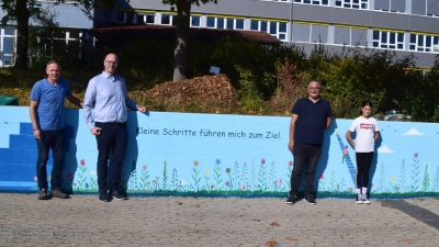 Mehrere Betonwände sind nun künstlerisch gestaltet. Das Bild zeigt (von links) Hausmeister Michael Lorenz, Bürgermeister Thomas Schmitt, Künstler Azar Valizada und Schülerin Laila Abd el Salam. (Foto: Gerhard Krämer)