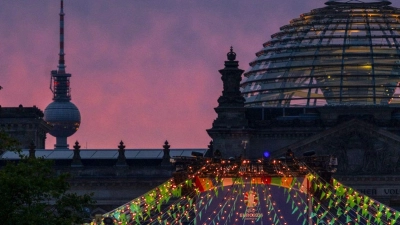 Der Schriftzug „Welcome to Berlin“ ist kurz vor Sonnenaufgang auf einem Display der Fanzone (Platz der Republik) vor der Kulisse des Reichstages und des Fernsehturmes zu lesen. (Foto: Soeren Stache/dpa)