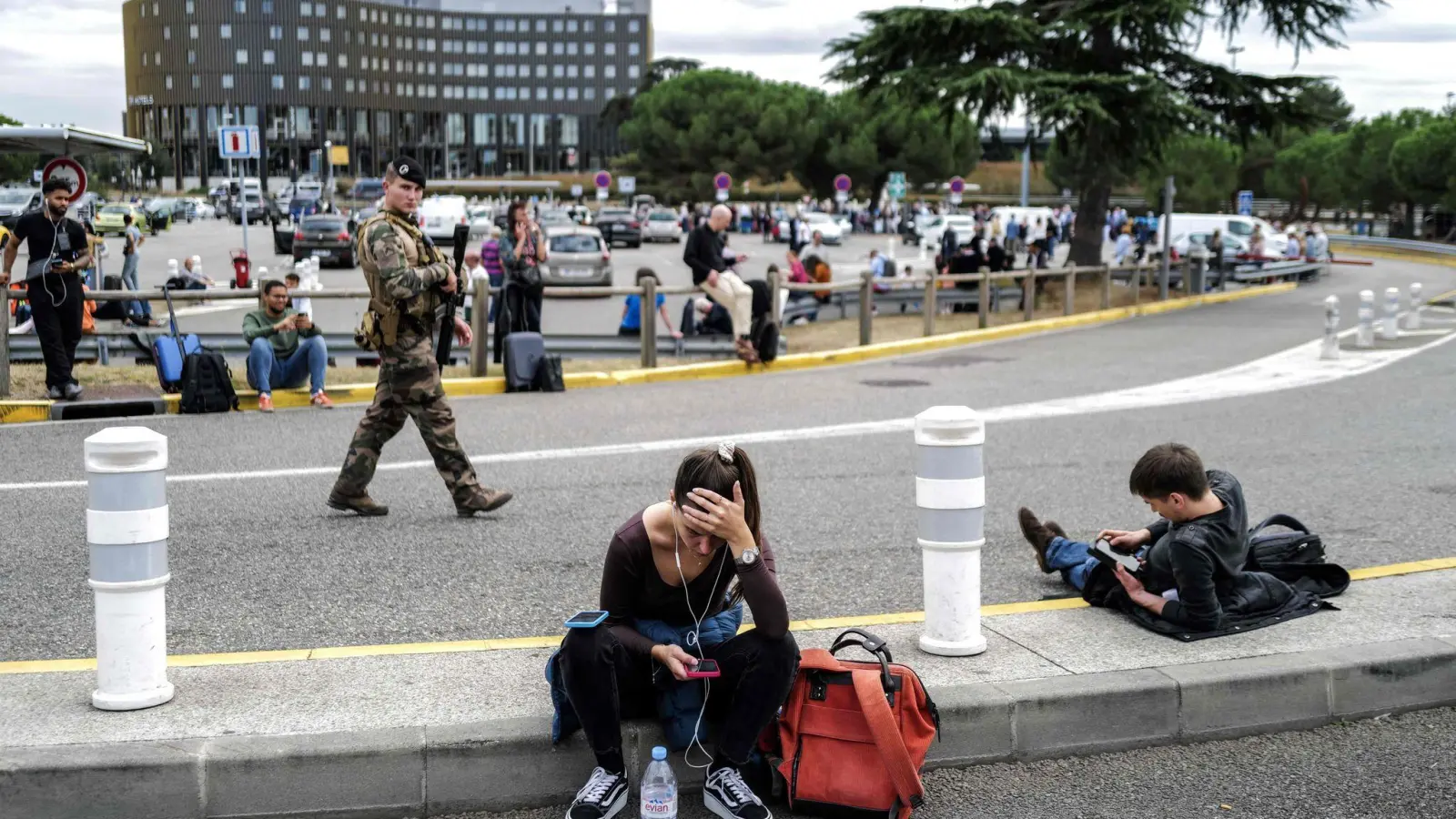 Reisende warten, während ein französischer Soldat vor dem Flughafen Toulouse-Blagnac patrouilliert. (Foto: Charly Triballeau/AFP/dpa)