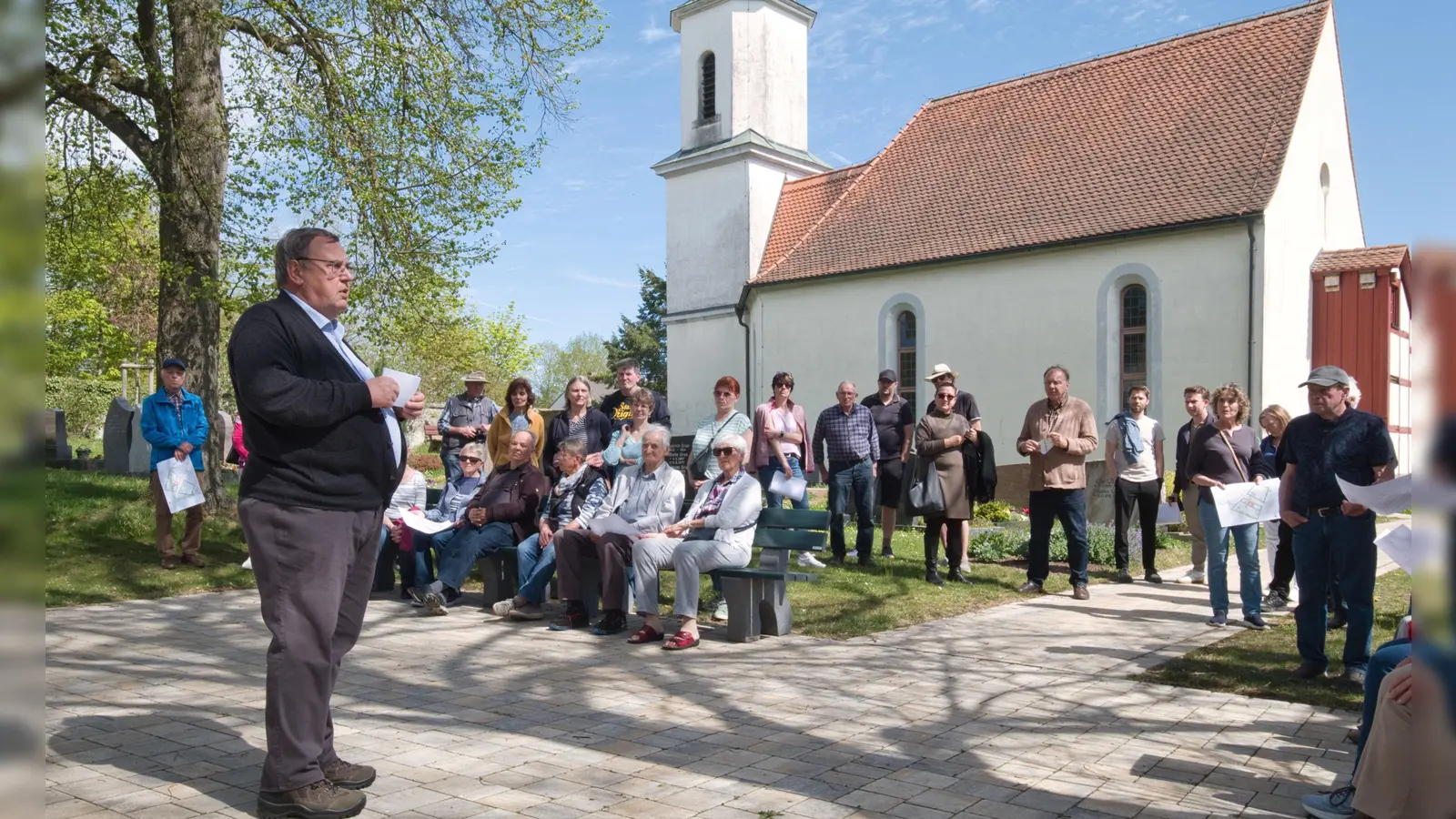 Fast 800 Jahre Friedhofsgeschichte: Werner Holzer bei seinem Vortrag am Platz vor der Leichenhalle mit Blick auf die Begräbniskapelle. (Foto: Martin Stumpf)