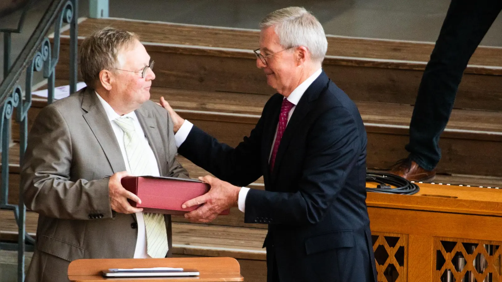 Vorsitzender Jürgen Fitschen (rechts) bedankt sich im Namen des Vereins der Freunde der Bachwoche Ansbach bei Dr. Andreas Bomba für seine Arbeit als Intendant und überreicht ein symbolisches Präsent. Der Weinkarton steht für Rebstöcke, die der Verein ihm schenkt. (Foto: Evi Lemberger)