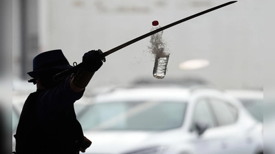 Joe Alexander zerteilt mit verbundenen Augen und einem Samurai-Schwert hochgeworfene Wasserflaschen, während des Weltrekordversuchs im Elbtor in der Hamburg Altona VW Niederlassung. Die Rekordversuche finden in Rahmen des siebzigsten Guinness World Records Day statt. (Foto: Marcus Brandt/dpa)