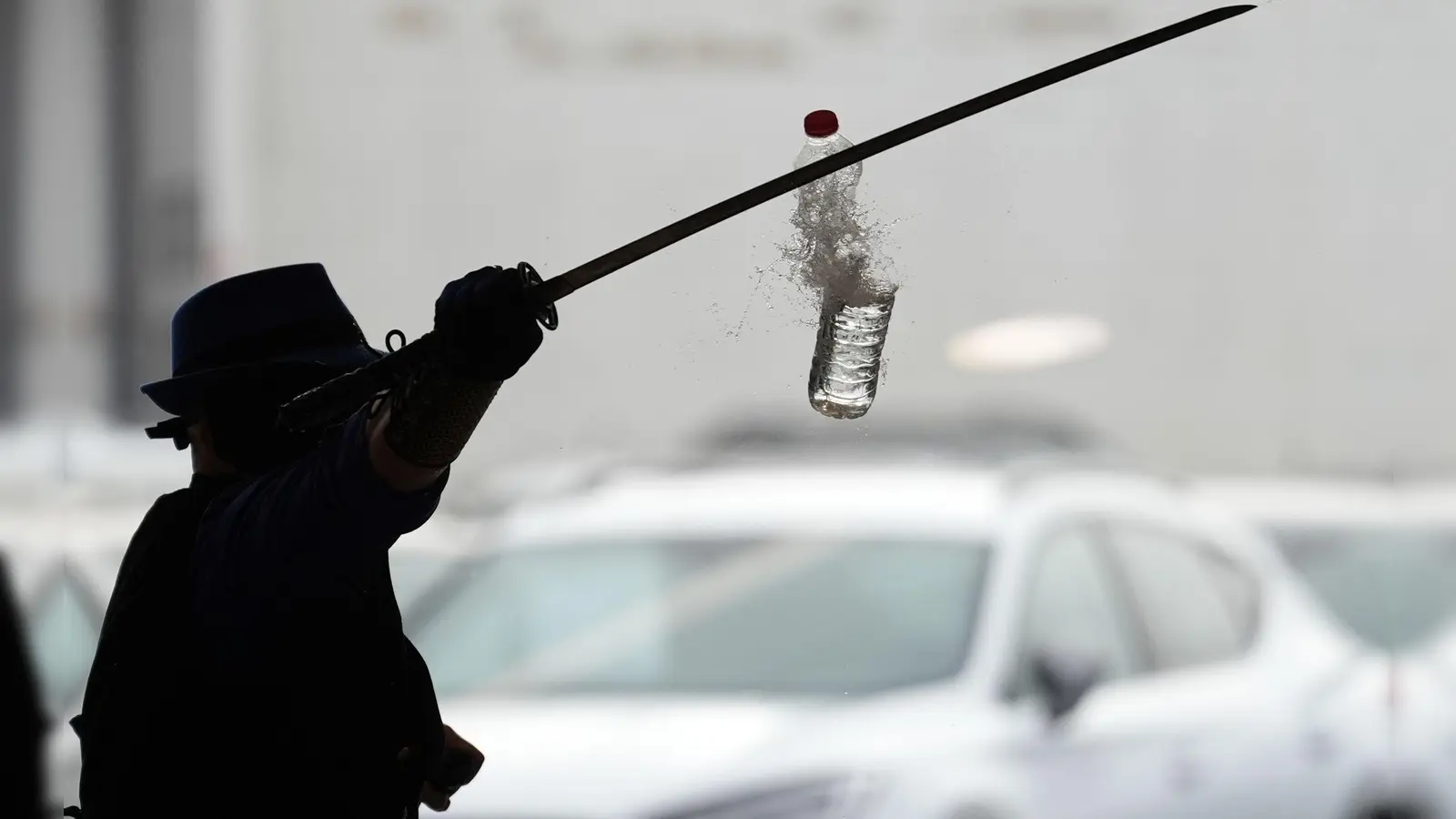 Joe Alexander zerteilt mit verbundenen Augen und einem Samurai-Schwert hochgeworfene Wasserflaschen, während des Weltrekordversuchs im Elbtor in der Hamburg Altona VW Niederlassung. Die Rekordversuche finden in Rahmen des siebzigsten Guinness World Records Day statt. (Foto: Marcus Brandt/dpa)