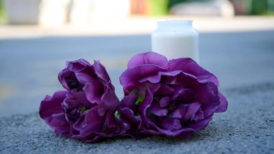 Blumen und eine Kerze liegen auf einem Schotterplatz vor dem Eingang zum Spielplatz, auf dem in der Nacht ein 17-Jähriger einen 14-Jährigen erstochen haben soll.  (Foto: Bernd Thissen/dpa)
