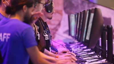 Messebesucher testen ein Computerspiel bei der Gamescom 2022.  (Foto: Oliver Berg/dpa)