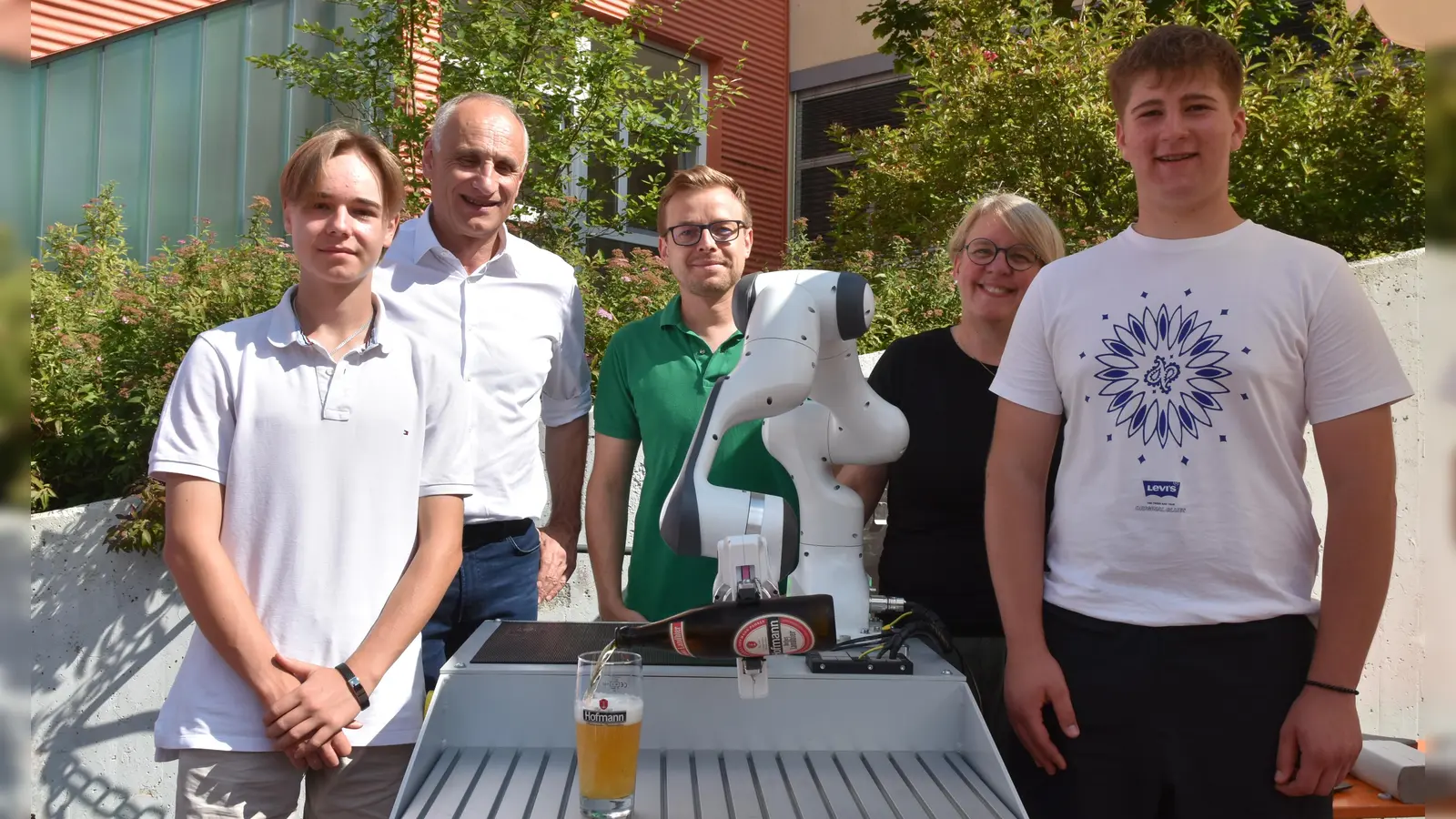 Nikita Hauck und Silas Stieb (links und rechts) haben zusammen mit ihrem Lehrer Christopher Härth (Mitte) einen Bierausschenkroboter programmiert. Darüber freuen sich Braumeister Georg Hofmann und Andrea Ort-Hack vom Werkzeugmaschinenhersteller, der den Roboterarm geliehen hat. (Foto: Anita Dlugoß)