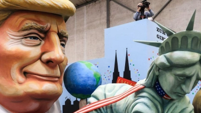 Einer der Wagen im Kölner Rosenmontagszug zeigt US-Präsident Donald Trump, der die Freiheitsstatue und die Justitia am Laufband führt. (Foto: Oliver Berg/dpa)