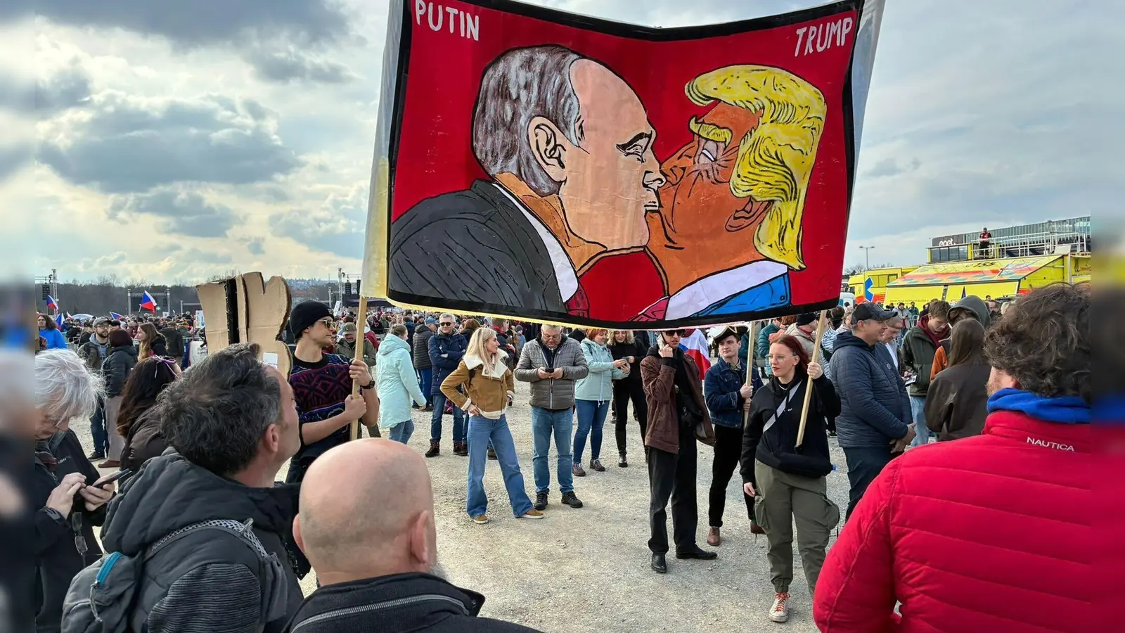 Demonstranten halten bei einer Kundgebung des Bündnisses „Eine Million Augenblicke für Demokratie“ ein Banner, auf dem sich stilisiert US-Präsident Trump und Russlands Präsident Putin küssen. (Foto: Michael Heitmann/dpa)